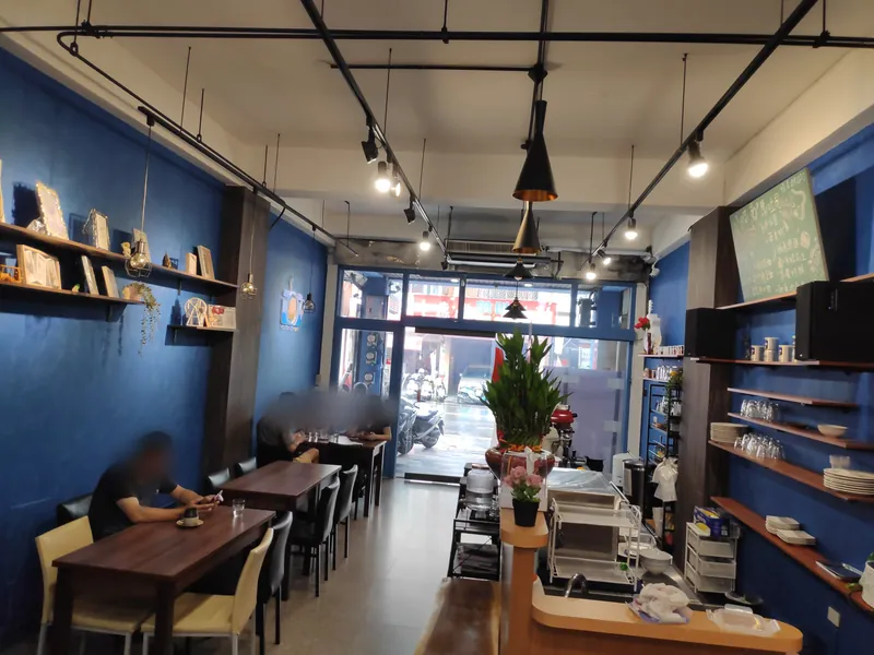 伶 Kopi 店裡：藍色的牆、木頭桌子、吊燈，最裡面是落地窗，2020 年 6 月剛開幕的樣子