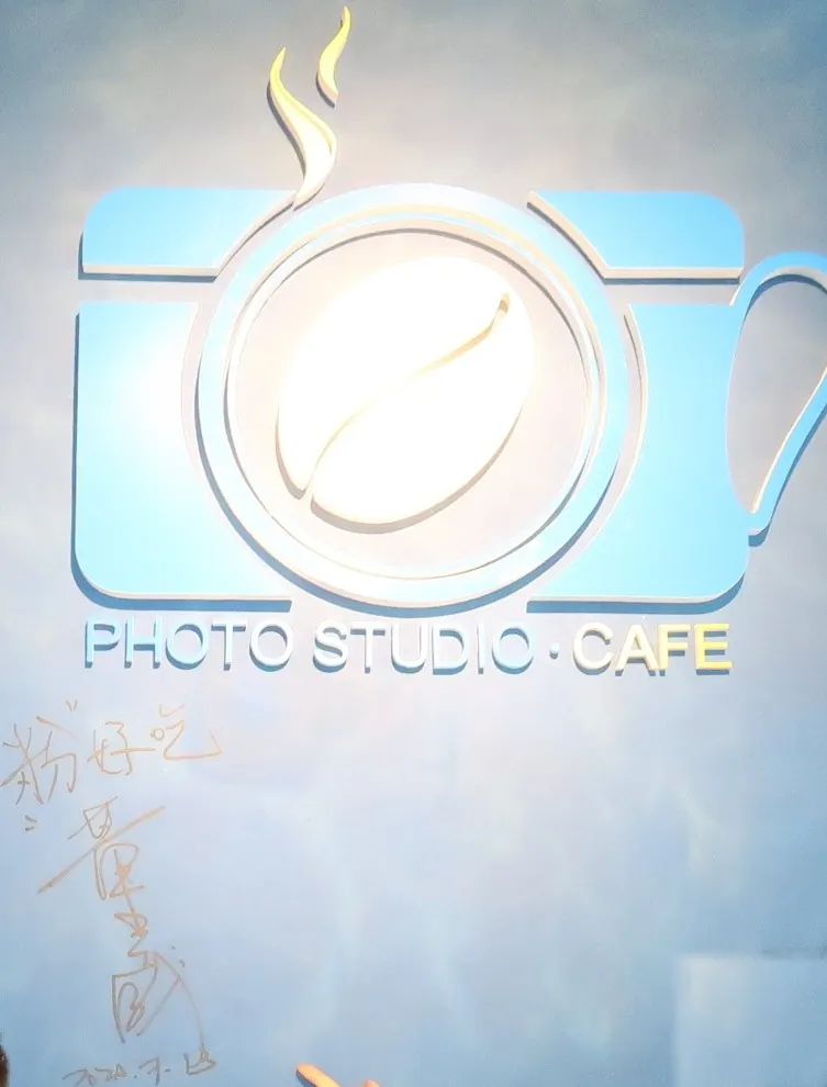 伶 Kopi 店裡的相機咖啡杯 Logo 牆，下面是主持人董至成 2020 年 7 月 13 日留下的簽名「粉好吃」