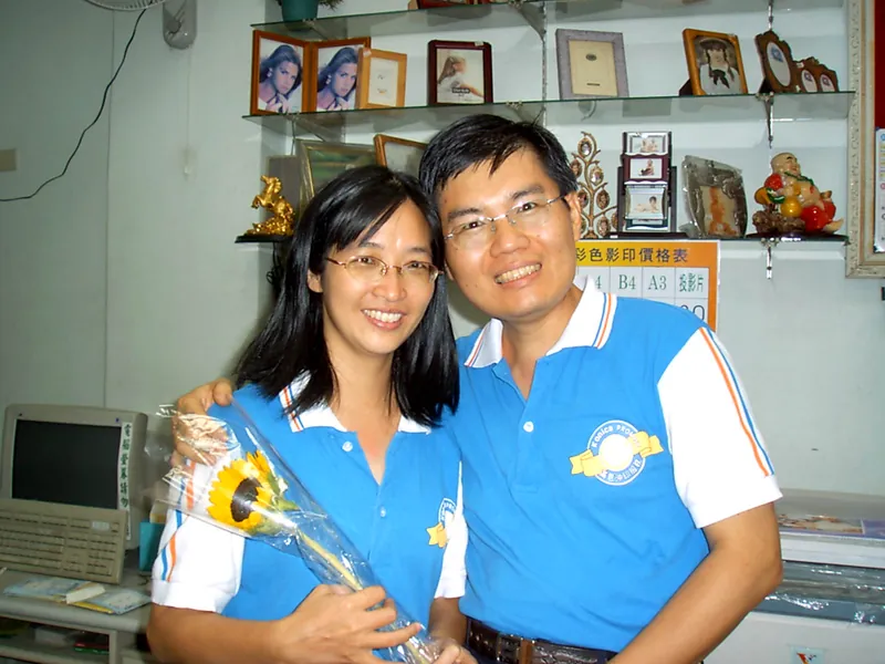 2004 年，老闆和老闆娘穿著恆美的制服，後面是相框牆